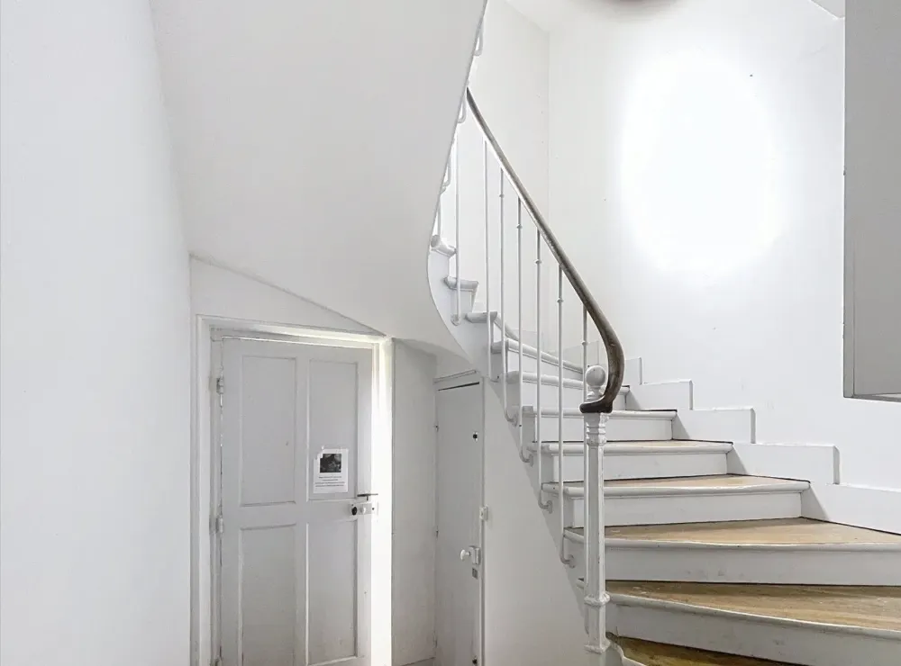Escalier commun en bois peint, rampe en fer forgé et sol en tomettes