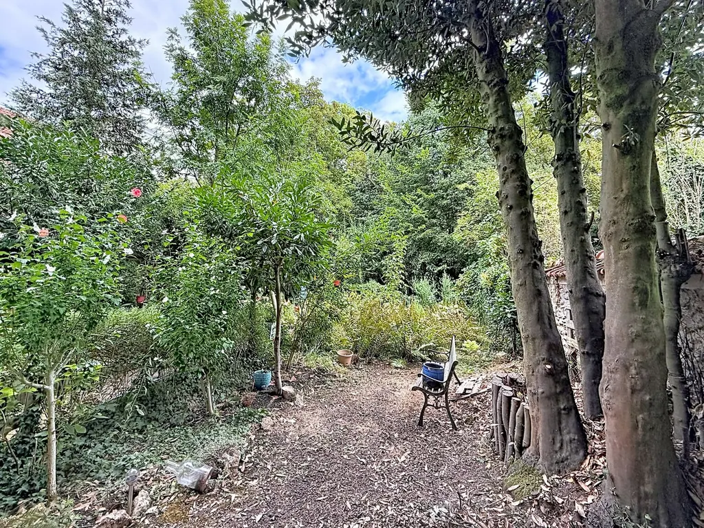 Jardin à l'arrière de l'immeuble, allée de gravier, banc en fonte et végétation