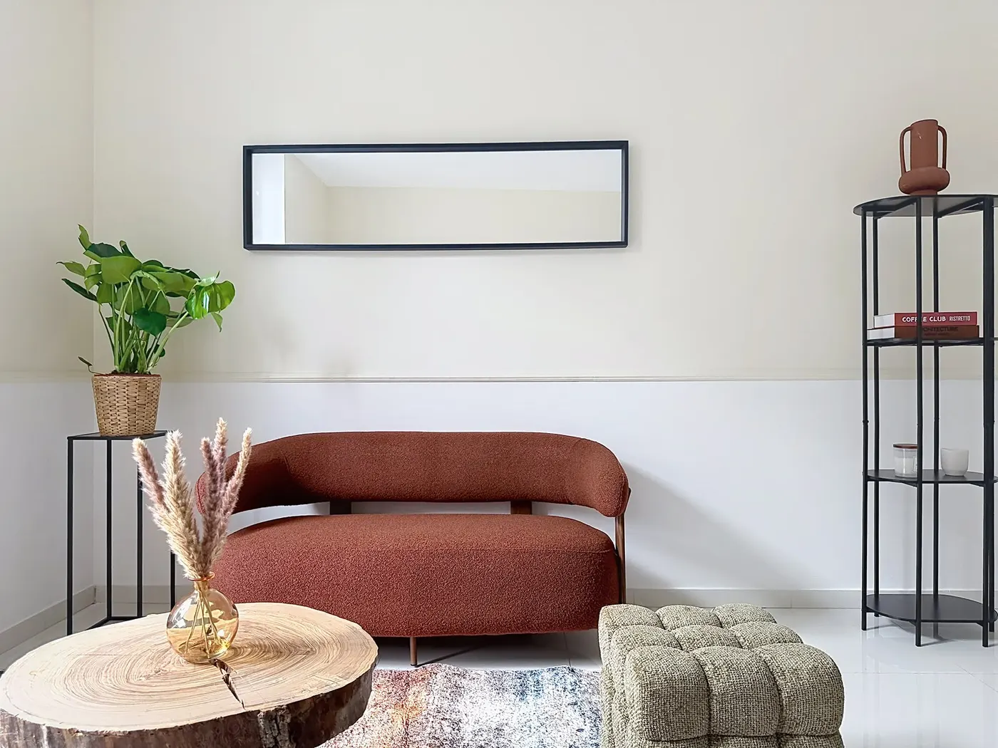 Séjour meublé de l'un des appartements, canapé terracotta, miroir et étagère noire