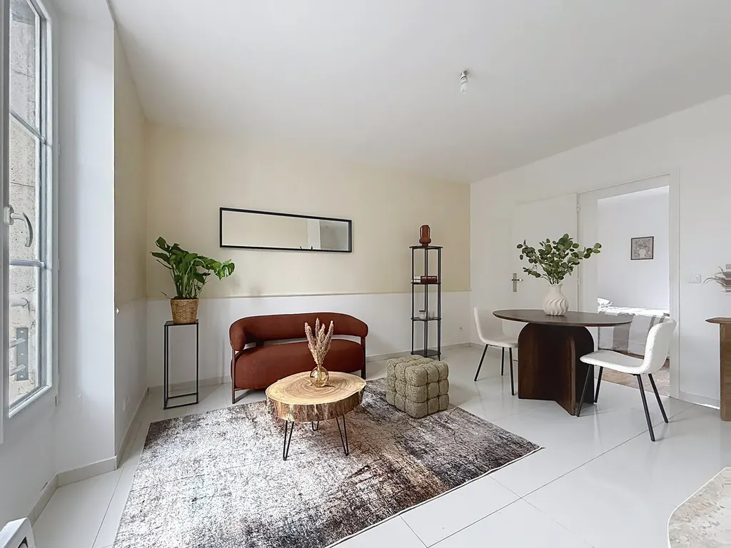 Séjour vu depuis la fenêtre, canapé, tapis et porte ouverte sur la chambre