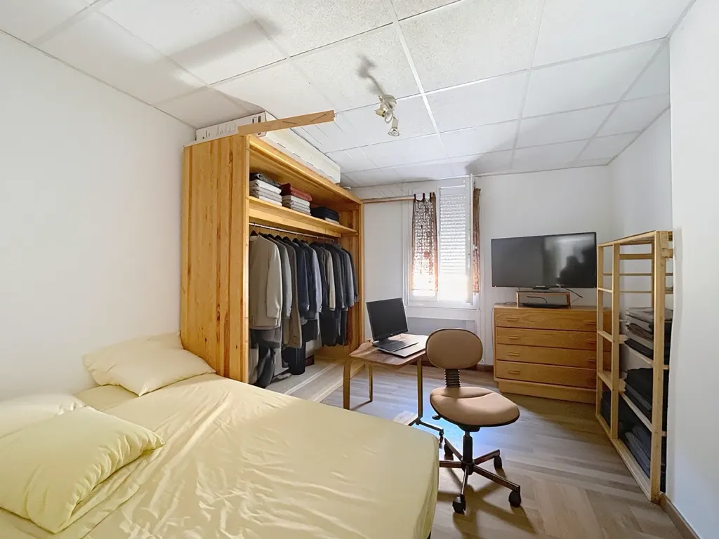 Chambre avec penderie en bois clair et coin bureau