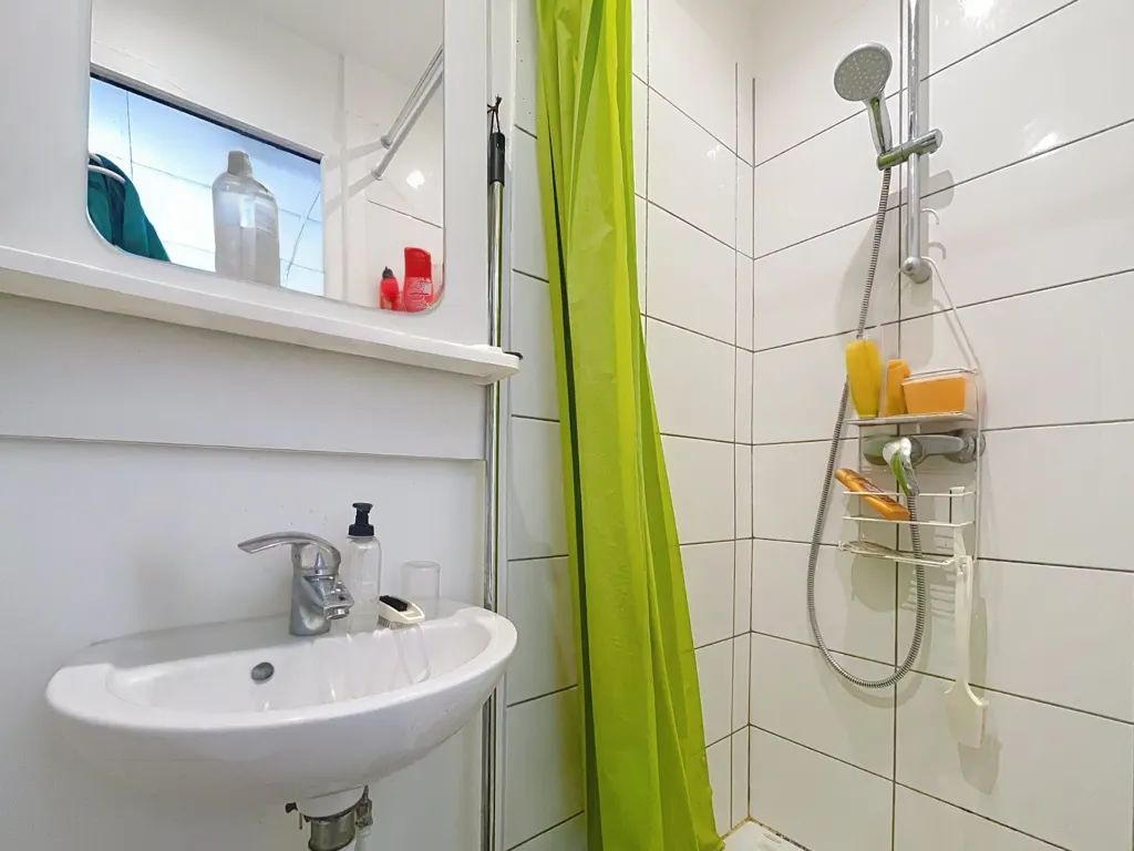 Salle d'eau carrelée avec cabine de douche et lavabo