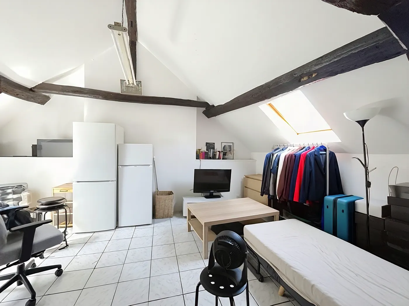 Studio sous combles avec fenêtre de toit et poutres apparentes