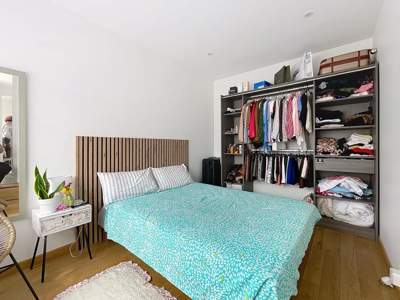 Chambre rénovée avec tête de lit en bois et dressing ouvert